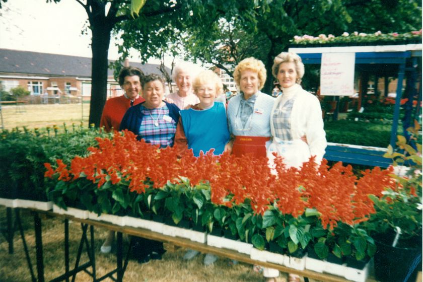 Image of ladies standing in front of a plant staff