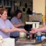 A photo showing a cafe counter and a customer being served
