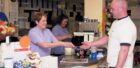 A photo showing a cafe counter and a customer being served