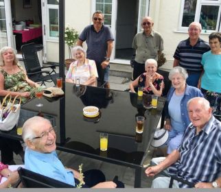 Photograph of a group of people sitting around a garden table