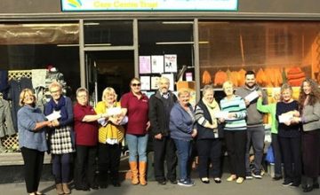A photograph of a group of volunteers standing in front of the charity shop