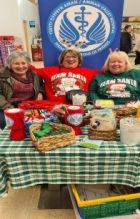 3 people sitting behind a table covered in craft items